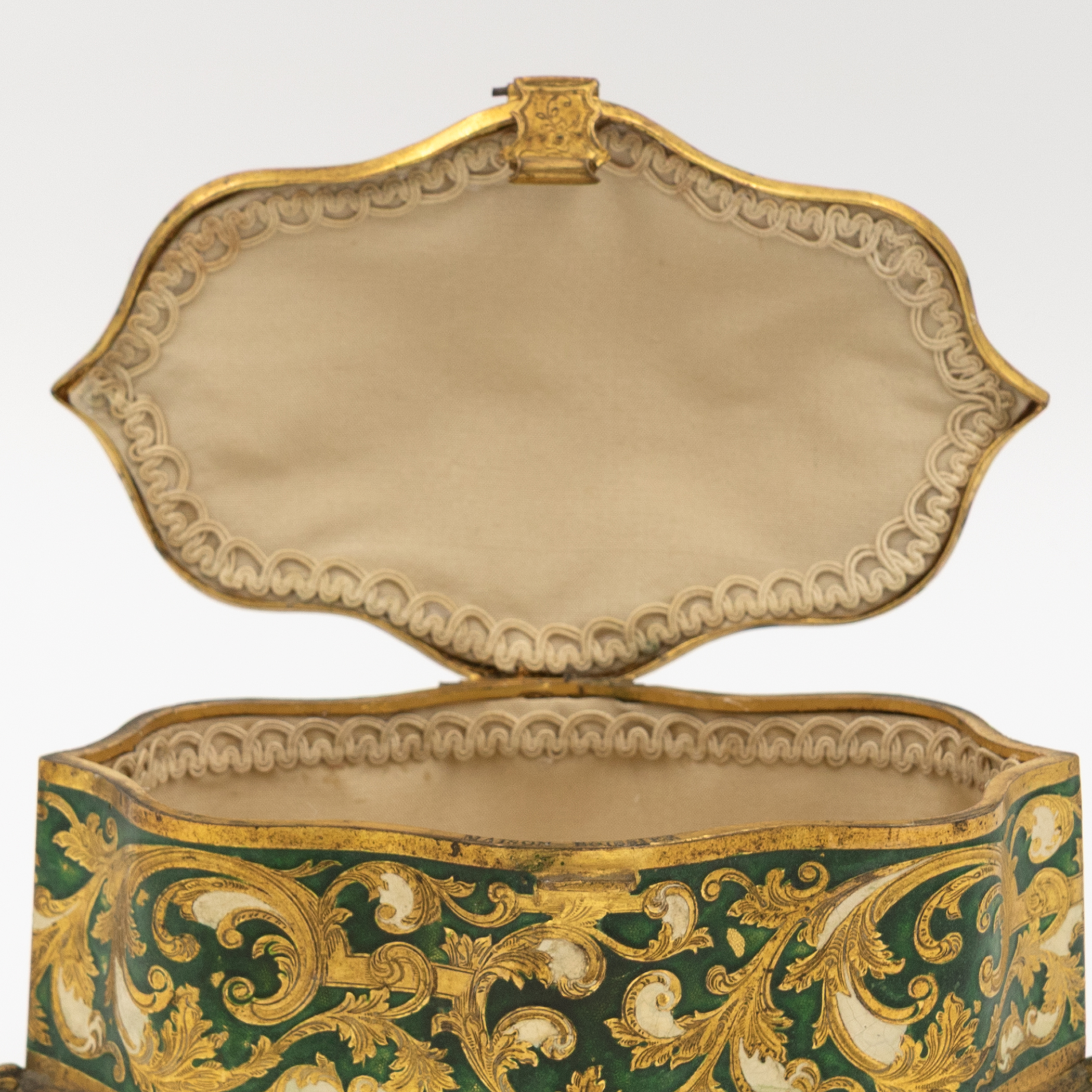 Interior of Maison Boissier gilt enamel jewelry box showing cream fabric lining and rouleaux border trim