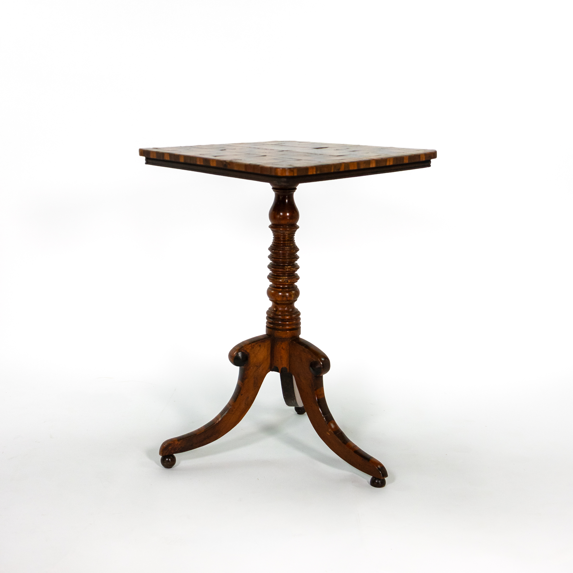 Three-quarter view of Regency English games table with inset chessboard, oyster veneer border and tripod base with bun feet.