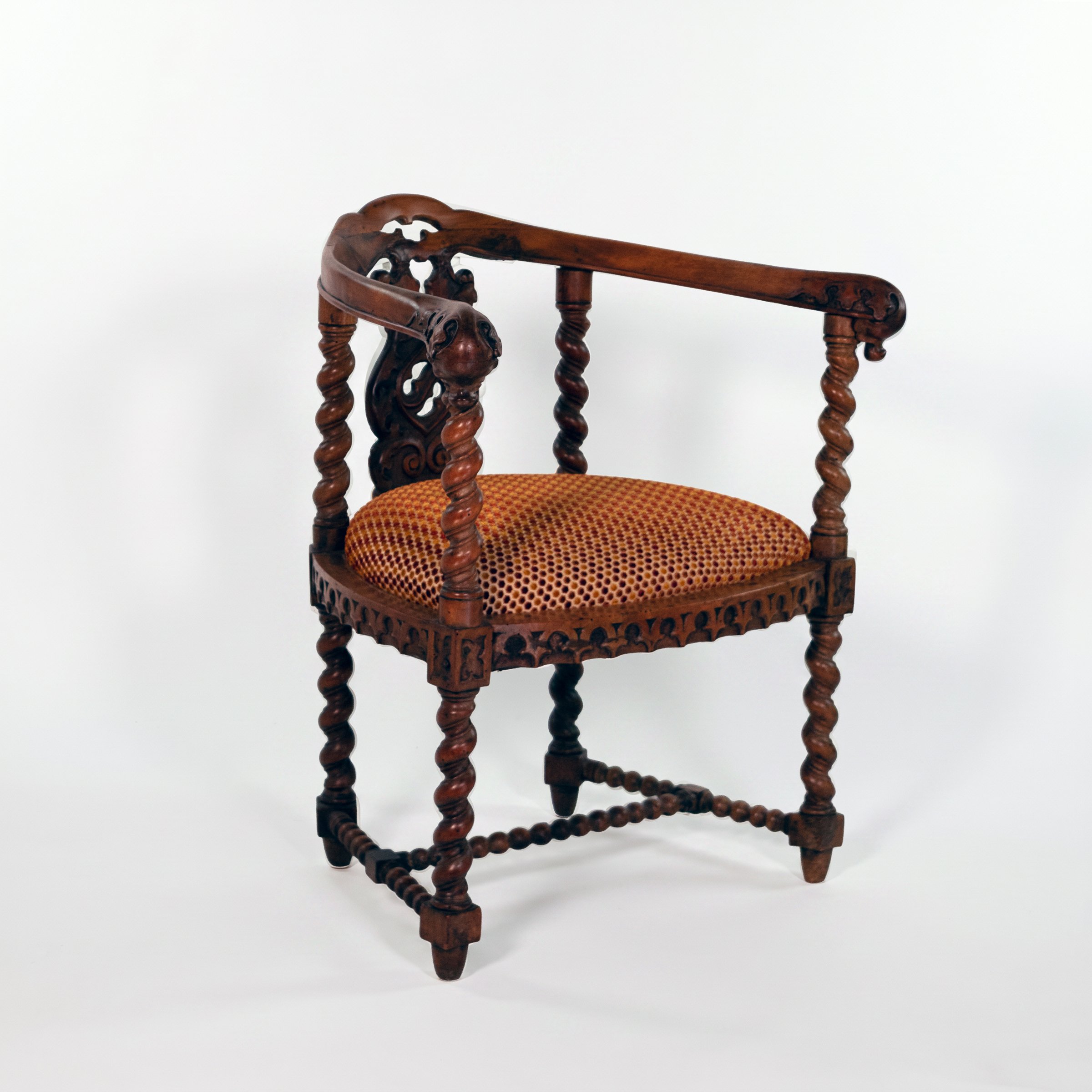Three-quarter front view of English Gothic Revival yew tub chair with carved Gothic apron