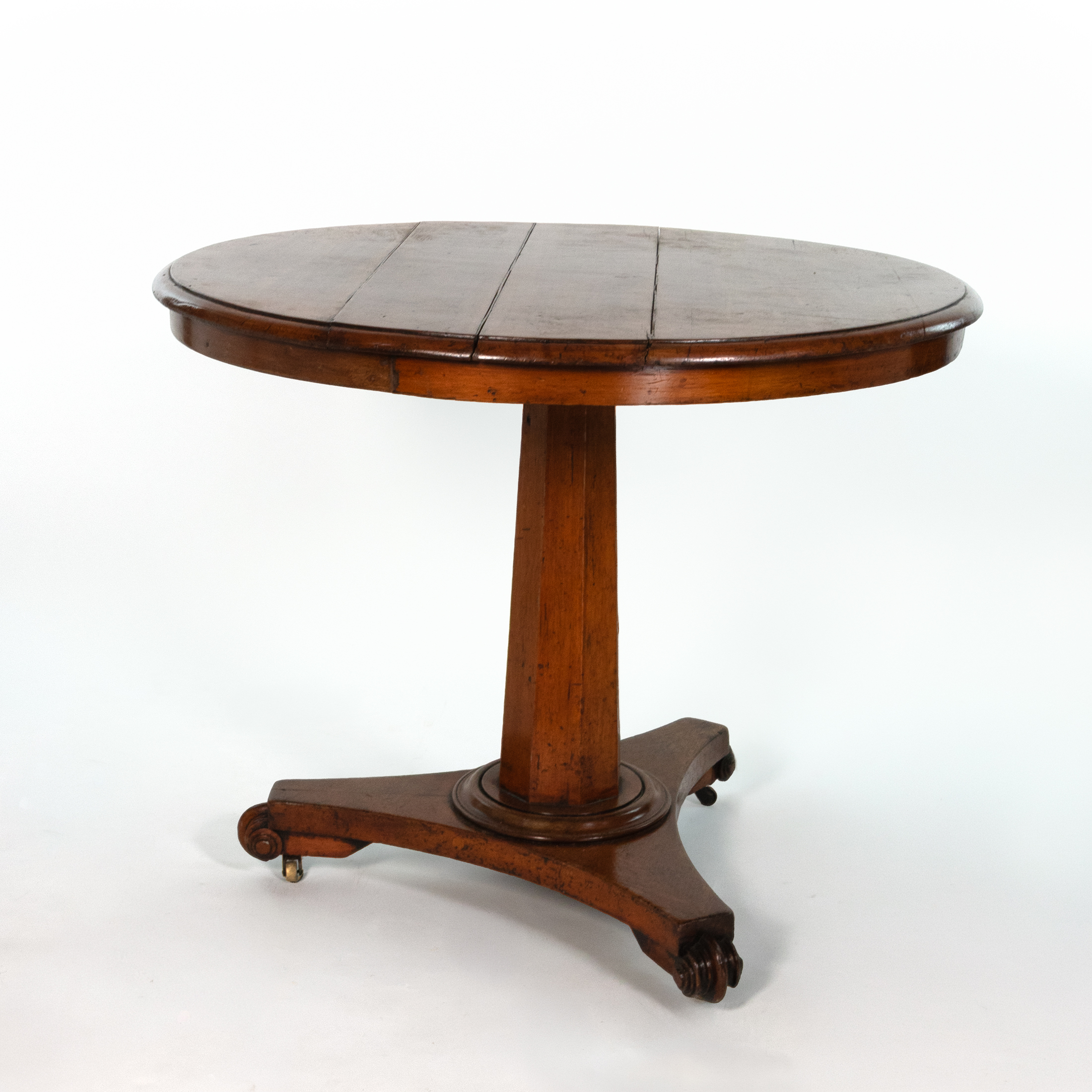Three-quarter view of an English fruitwood center table, circa 1850, with octagonal pedestal and tripod base