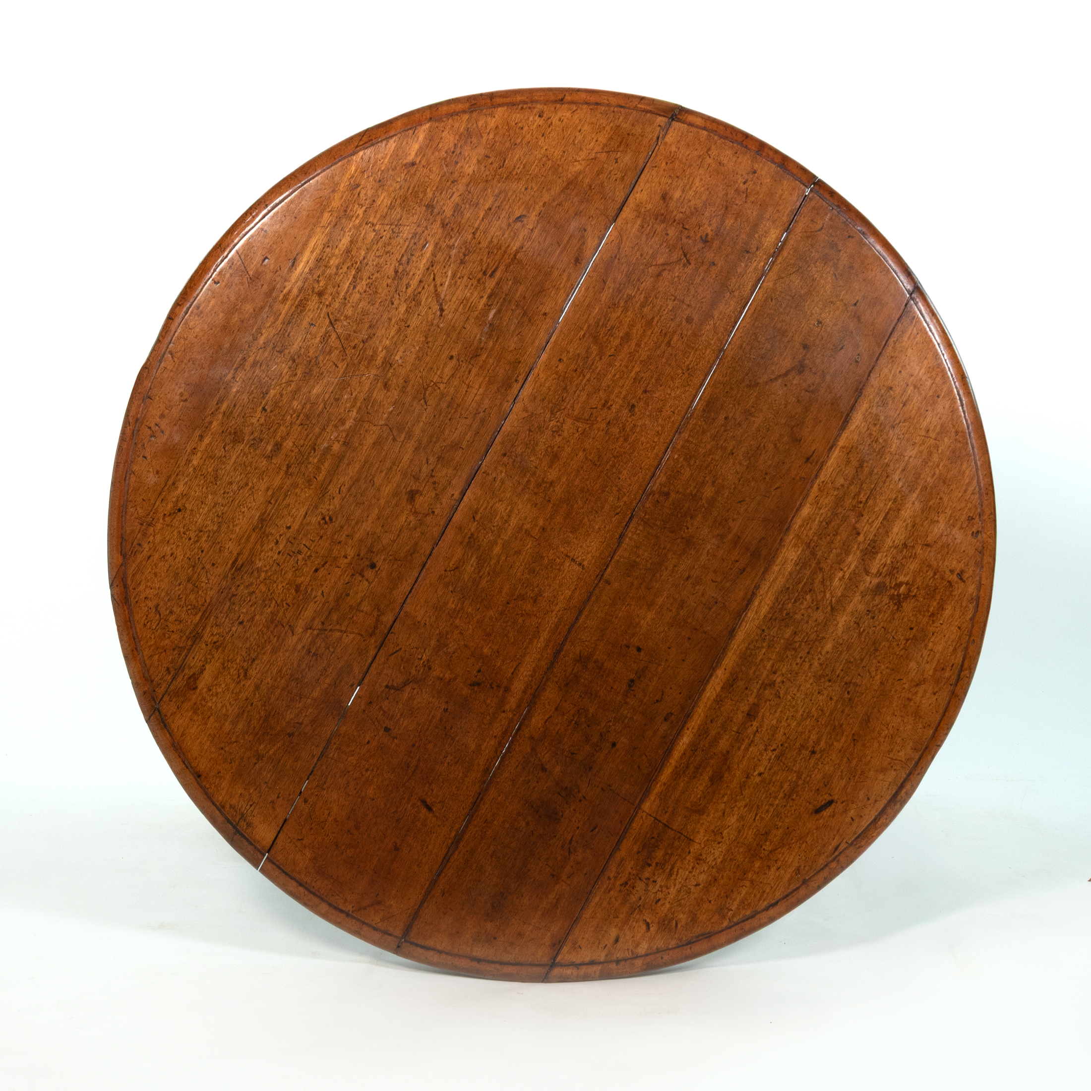 Round plank-built top of an English fruitwood center table, circa 1850, showing wood grain and molded edge