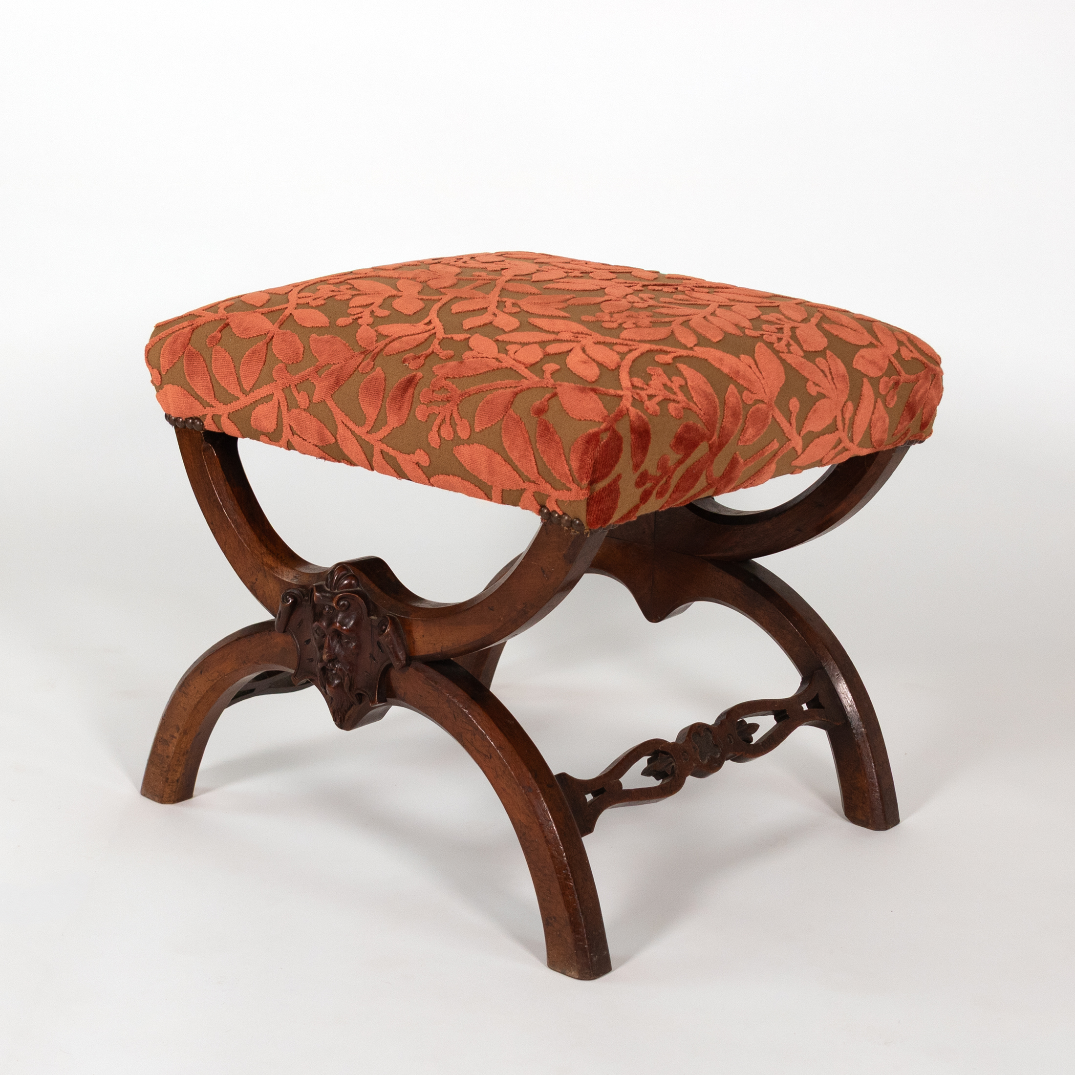 Carved walnut curule-form stool, angled view showing X-frame and bearded mask, French circa 1830