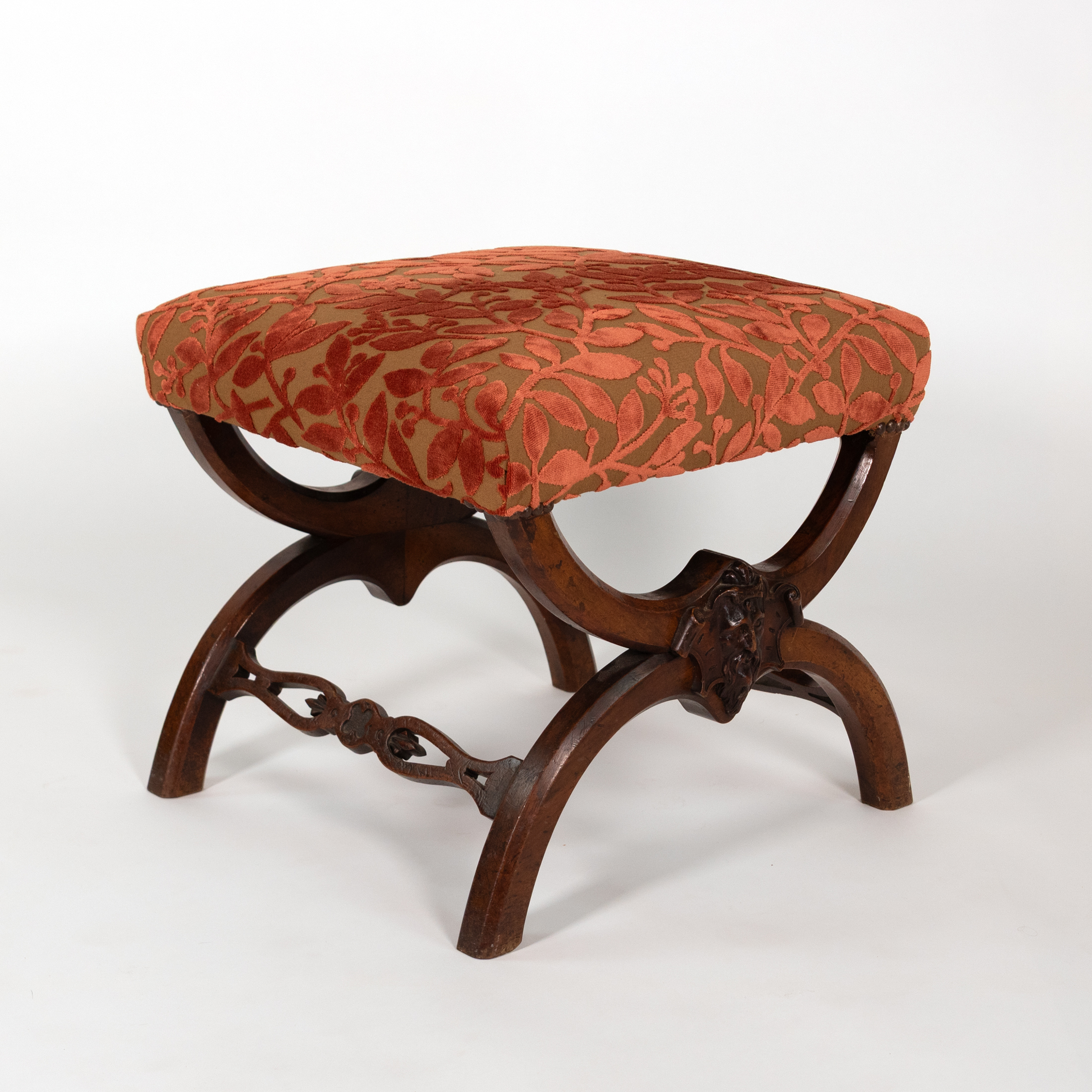 Carved walnut curule-form stool, three-quarter view, French circa 1830, with cut velvet seat