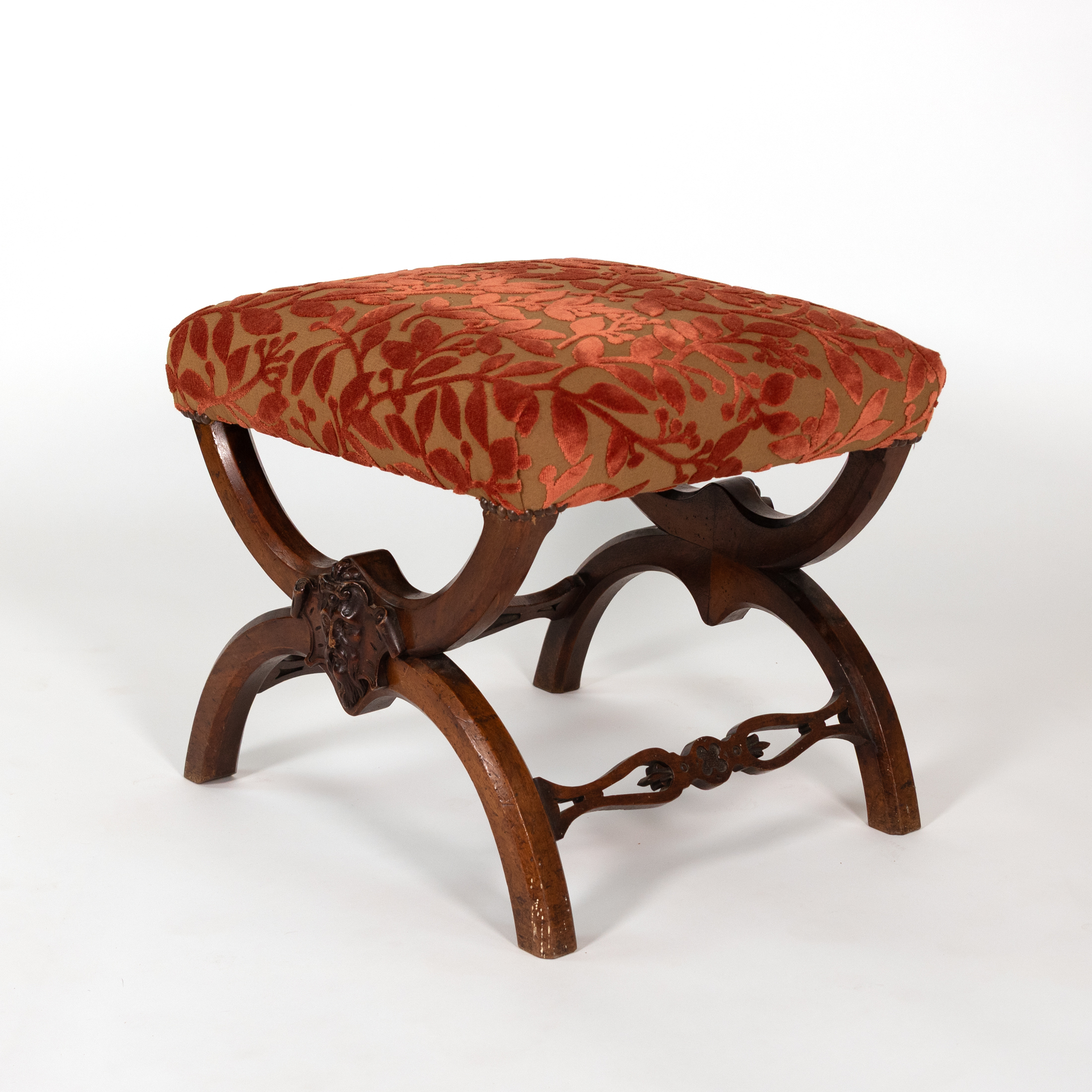 Carved walnut curule-form stool, angled view showing depth and pierced stretcher, French circa 1830