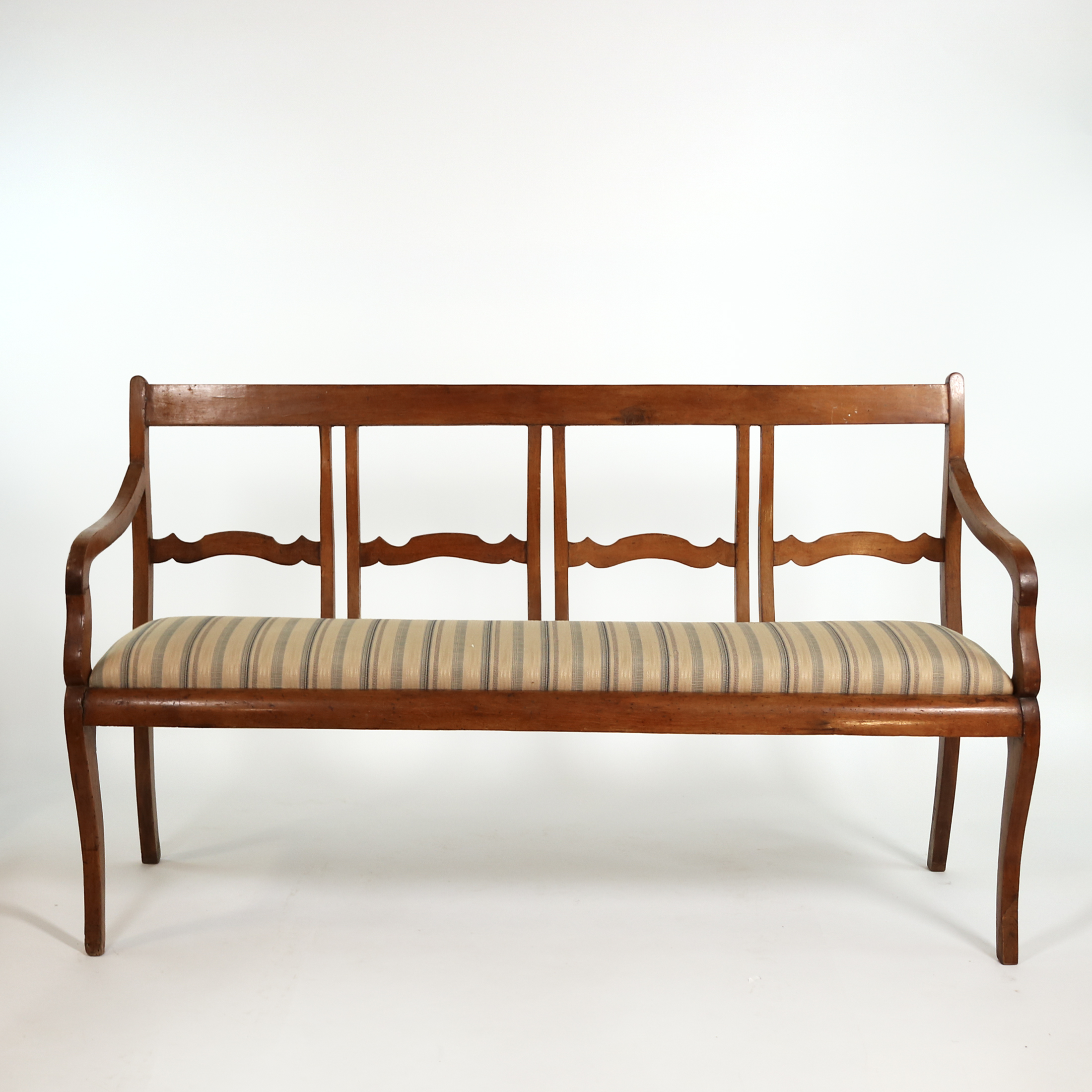 Front view of Italian walnut bench circa 1880 with scalloped open back and striped upholstered seat