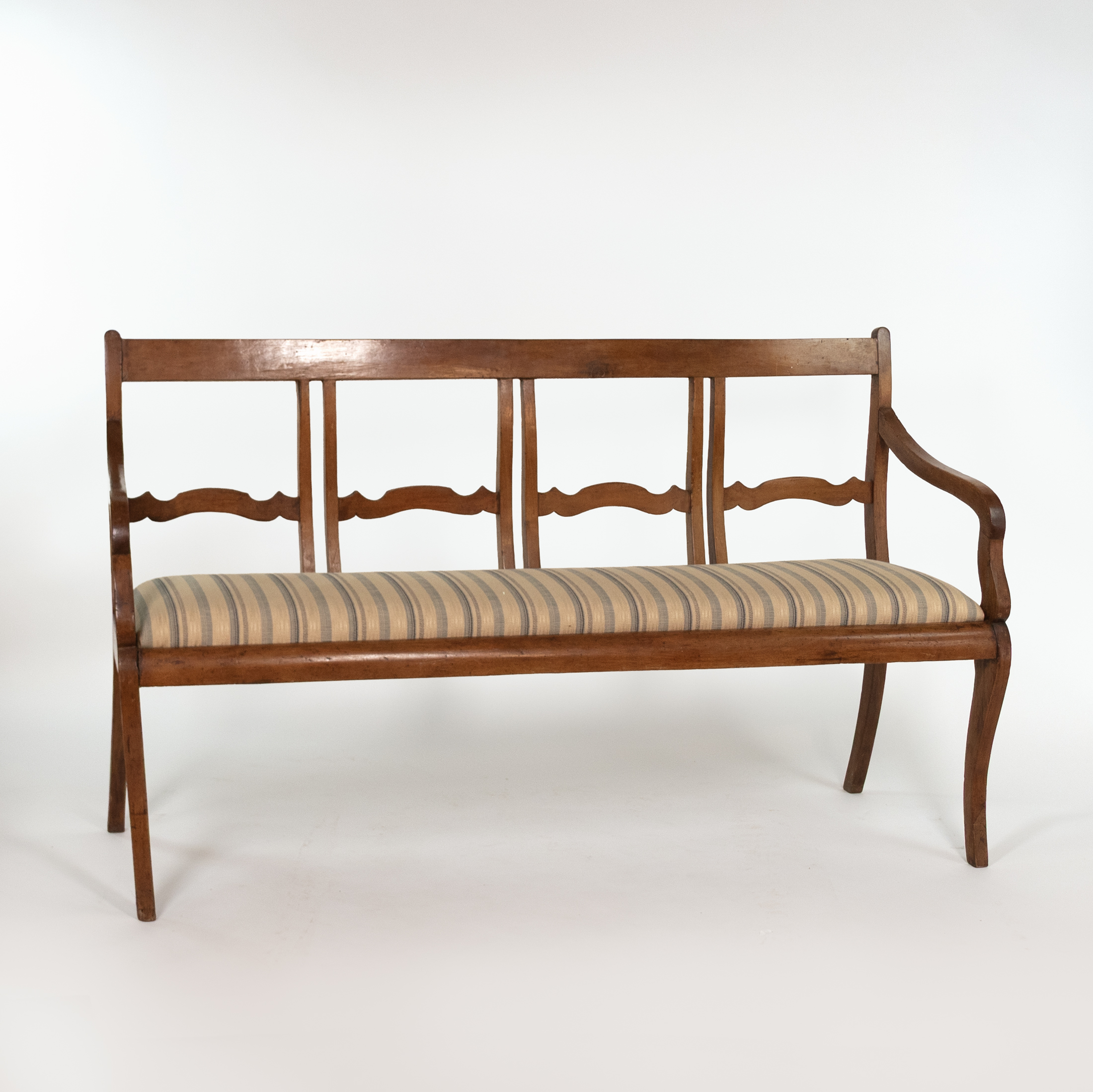 Front view of Italian walnut bench circa 1880 with scalloped back, striped seat and curved arms
